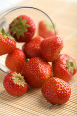 ripe strawberries falling from glass bowl