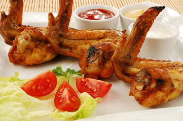 Grilled chicken wings with baked potatoes and vegetable salad