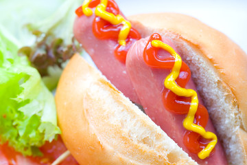 Mini hot dog with mustard and ketchup served with fresh salad