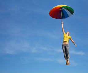 Flying girl with colorful umbrella in the blue blue sky