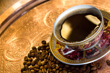 Café chaud dans une tasse et grains sur un plat asiatique en cuivre