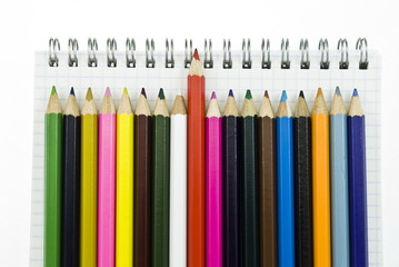 colorful pencils on the blank spiral notepad