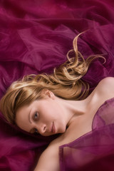 Lying woman with light hair on a claret background
