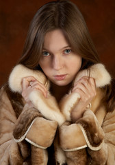 The girl in a fur coat on motley background