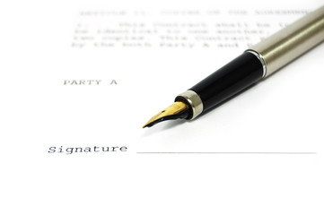 A document with a place for a signature and a gold nibbed pen
