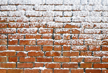 Snow sticking to an old brick wall.