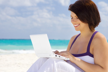 woman with laptop computer on the beach