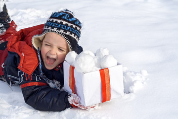 Happy boy in the snow with a box of snowballs