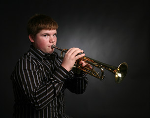 teenage boy playing trumpet and wearing striped shirt