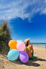 young woman with colorful balloons on the beach