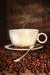 White coffee cup with spoon on roasted beans