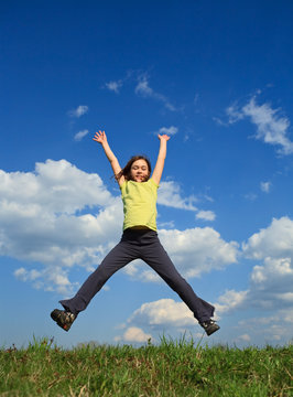 Girl jumping, running outdoor against blue sky