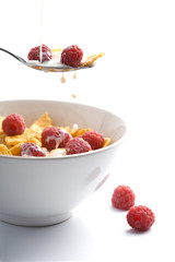 milk pouring onto muesli with raspberry isolated