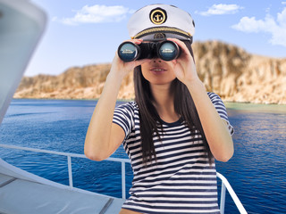 Young woman standing on the yacht is looking through