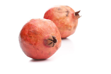 Ein Granatapfel vorne einer hinten auf weiß