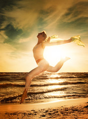 Fototapeta na wymiar Beautiful young woman jumping on a beach at sunset