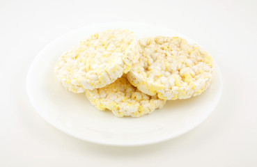 Three rice cakes on a white plate for a snack.