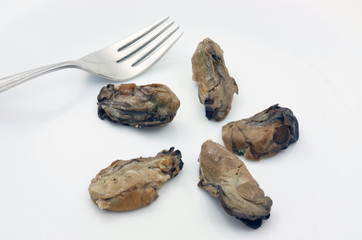 Five delectable smoked oysters on a plate with a fork.