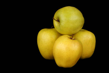 Four yellow apples on a black background