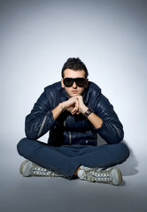 young trendy man wearing leather jacket and sunglasses