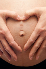 pregnant woman with her hands forming a heart symbol for love