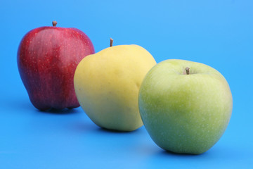 Three multi-coloured apples on a blue background