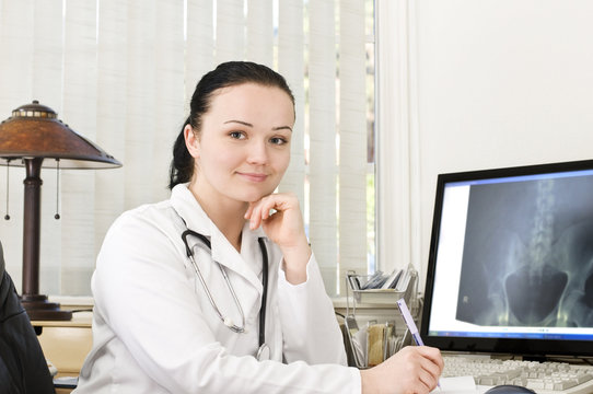 Portrait of female doctor sitting at the table with x-ray scan o