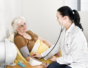Senior lady having his blood pressure checked by a doctor