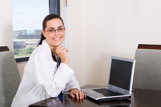 young female doctor sitting by her laptop computer