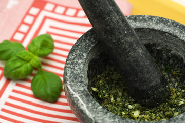 mortar with pesto sauce and basil leaves