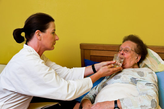 Pfleger betreut alte Frau im Altersheim