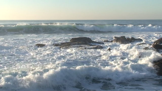 Agitated sea waves against rocks in the beach