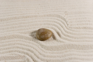 Fototapeta na wymiar Closeup of a pebble on white sand (Zen style)