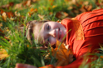 little girl laying on autumn leaves and smiling