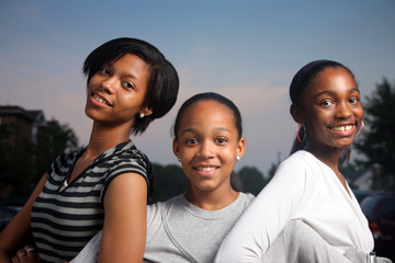 Three beautiful smiling teenage African American girls outdoors