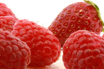 raspberries and strawberry closeup on white background