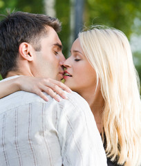 Young happy amorous couple kissing, outdoors