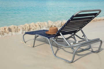 Straw hat  on lounge chair on tropical island beach resort