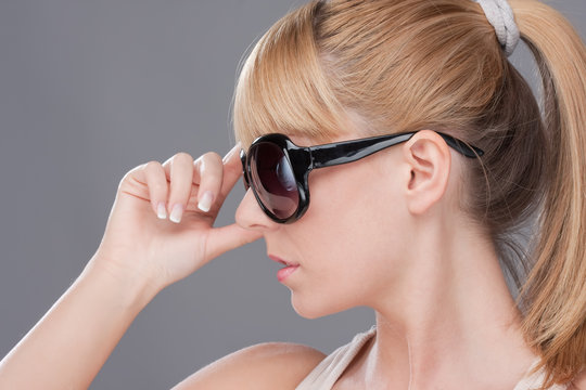 Young blond woman holding modern sunglasse