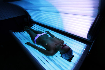 Beautiful young white woman tans in solarium