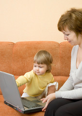 Mother with daughter on sofa with laptop