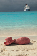 Tropical island beach with cruise ship and straw hat