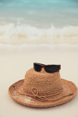 Straw hat and sunglasses on tropical island beach resort