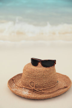 Straw hat and sunglasses on tropical island beach resort