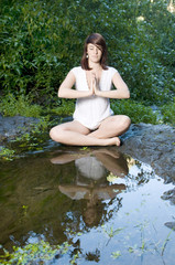 woman in yoga position near a pond