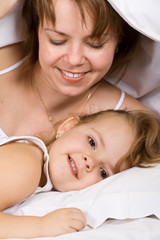 Happy mother and kid lazying under the blanket