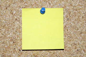 Blank yellow sticky note on corkboard