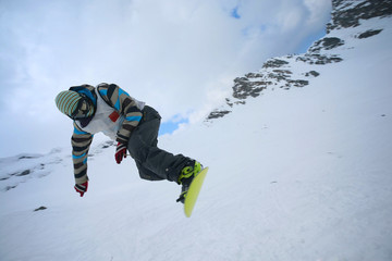 Male snowboarder jumping of a hill