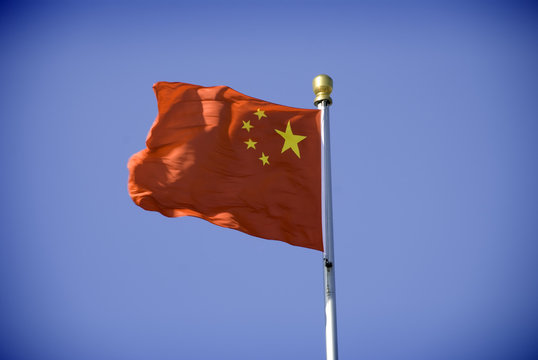 A chinese flag blows in the wind on a bright sunny day