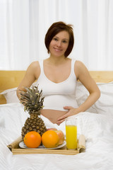 Obraz na płótnie Canvas Young pregnant woman has a breakfast in the bed